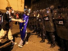 Демонстранты стоят перед полицейскими во время акции протеста против законопроекта об 